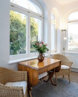Un comedor con una mesa de madera, sillas de mimbre y un jarrón de flores.