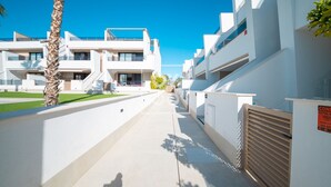 En moderne boligbygning med en ren, hvid facade, en central gårdhave og en klar blå himmel.
