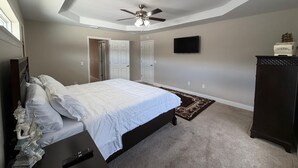 A bedroom with a bed, a ceiling fan, a TV, and a dresser. - Spacious 4-bedroom house in perfect Ocala with cool AC (Ocala)
