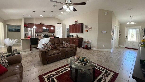 A spacious living room with a brown leather sofa, a glass coffee table, and a red patterned rug. - Spacious 4-bedroom house in perfect Ocala with cool AC (Ocala)