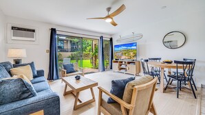 Een moderne woonkamer met een bank, salontafel en eethoek.