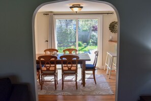 Un área de comedor con una mesa y sillas, un tapete estampado y vistas a un patio trasero a través de una puerta.