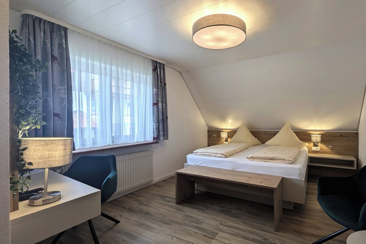 Una camera moderna e luminosa con un letto, comodini, una scrivania e una sedia.