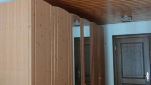 A room with wooden paneling, a ceiling light fixture, a door, and a bench.
