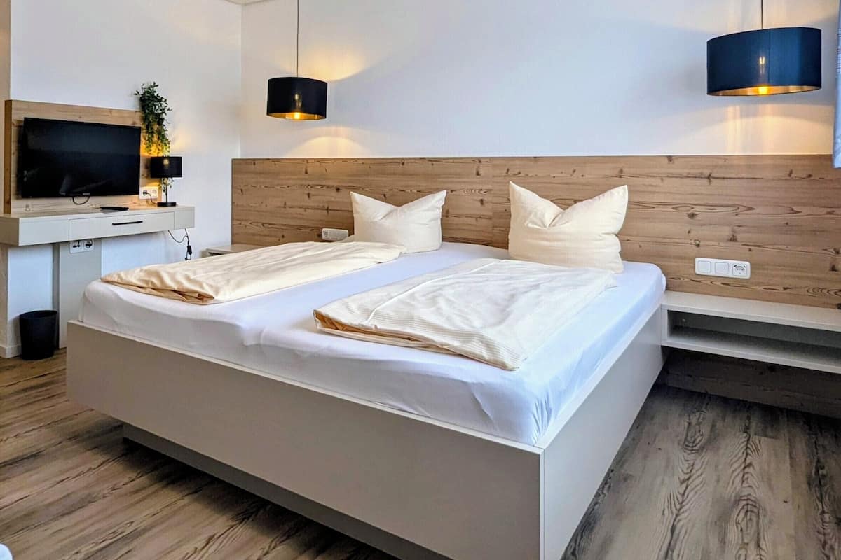 Camera d'albergo moderna con un grande letto, una TV a schermo piatto, una scrivania e una testata del letto in legno.