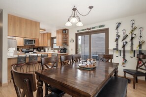 A modern kitchen with wooden cabinets, a dining table, and chairs. There are skis mounted on the wall. - Perfect 3 bedroom family home, views, game room, pet friendly! (Grand Lake)