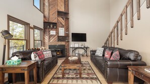 A living room with leather sofas, a wooden coffee table, and a fireplace. - 874 Kinnikinnick Rd Perfect 3 bedroom family home, views, game room pet friendly (Grand Lake)