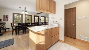 A kitchen with wooden cabinets, a large island, and a dining area with a table and chairs. - 874 Kinnikinnick Rd Perfect 3 bedroom family home, views, game room pet friendly (Grand Lake)