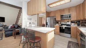 A modern kitchen with wooden cabinets, stainless steel appliances, and a central island with bar stools. - 874 Kinnikinnick Rd Perfect 3 bedroom family home, views, game room pet friendly (Grand Lake)