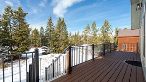 A wooden deck with a metal railing overlooking a snowy landscape and trees. - 874 Kinnikinnick Rd Perfect 3 bedroom family home, views, game room pet friendly (Grand Lake)