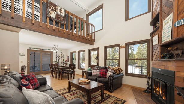 A spacious living room with a fireplace, a dining area, and a loft with a balcony. - 874 Kinnikinnick Rd Perfect 3 bedroom family home, views, game room pet friendly (Grand Lake)