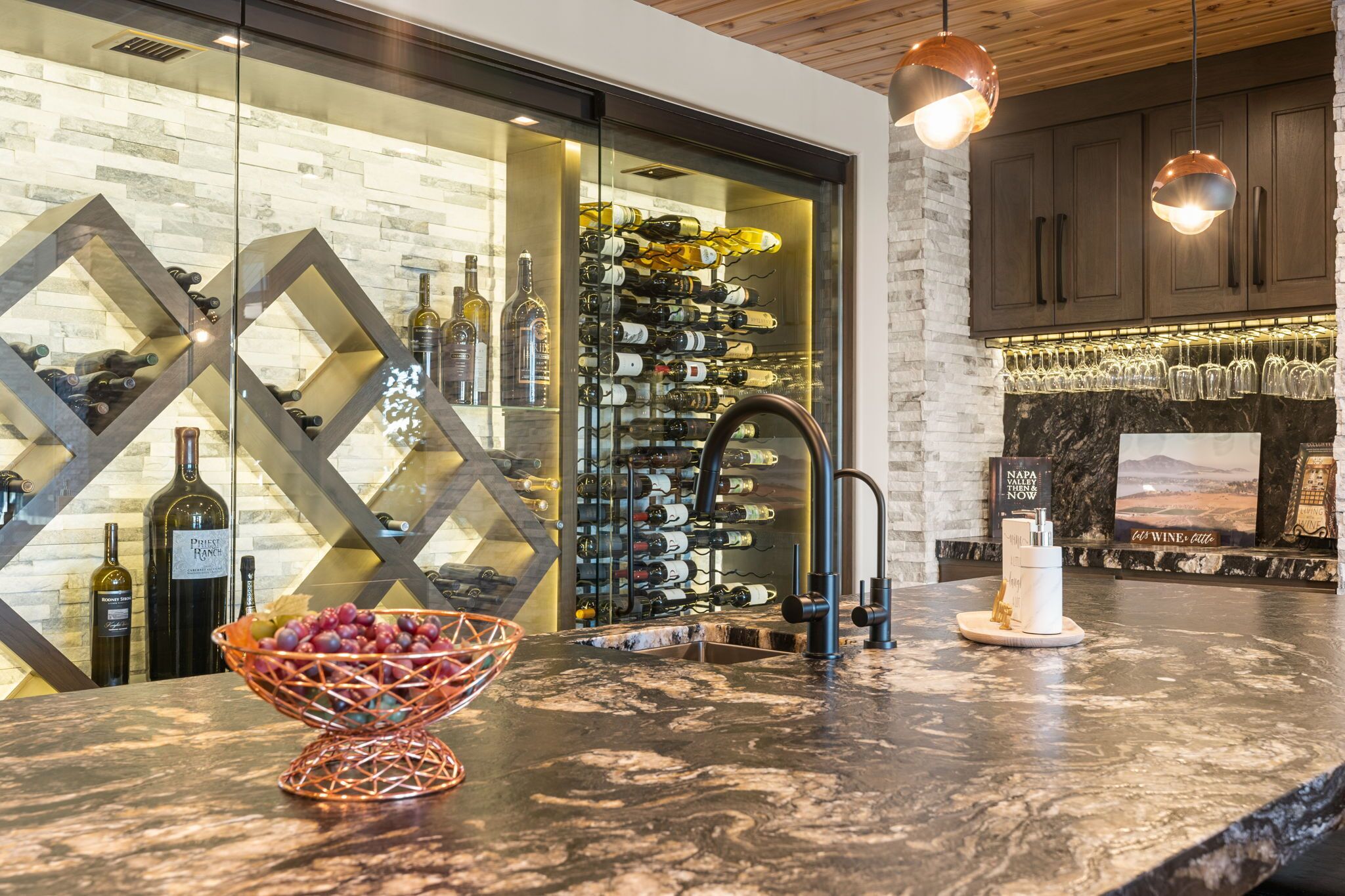 Un bar à vin doté d’un comptoir en marbre, d’étagères à bouteilles et d’une vitrine réfrigérée.