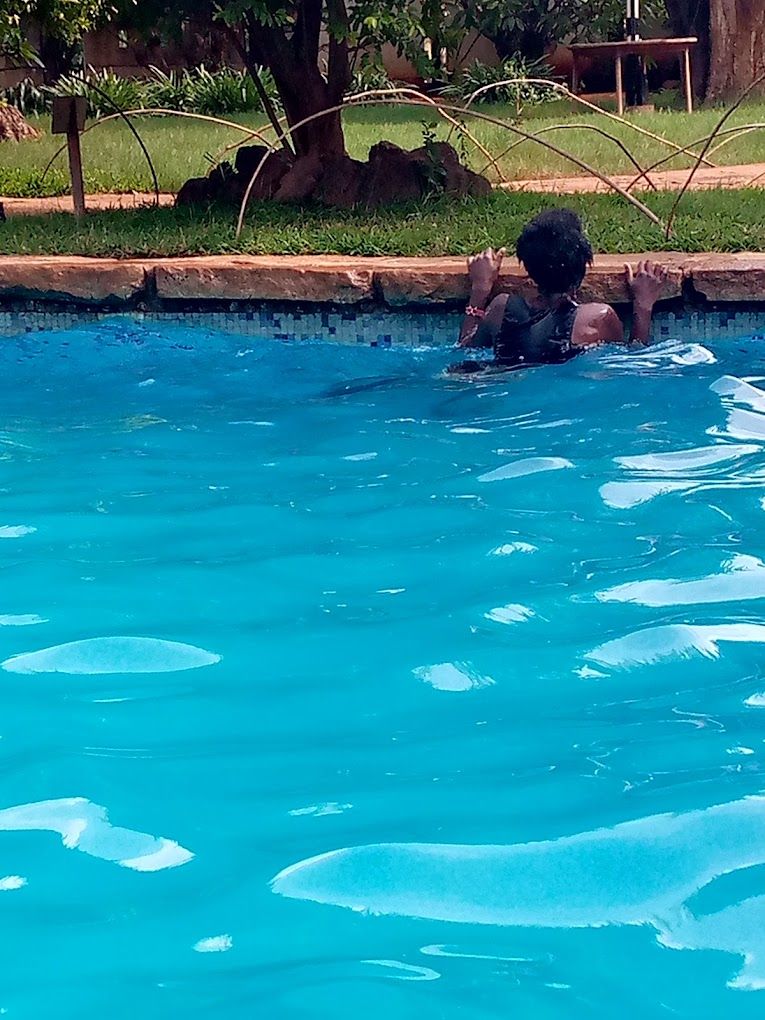 Una piscina con agua azul cristalina y una persona nadando.