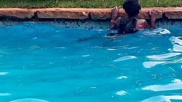 Una piscina con agua azul cristalina y una persona nadando.