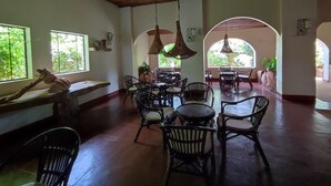 A spacious dining area with high ceilings and natural light from large windows.
