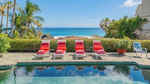 A poolside area with lounge chairs, a view of the ocean, and a building in the background. - Los Cabos Villa Steps to Beautiful Beach | Private Pool & Ocean Views (Turistico Corredor)