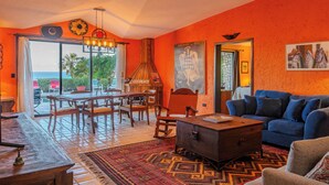 A room with a blue sofa, wooden furniture, a patterned rug, and a view of the outdoors. - Los Cabos Villa Steps to Beautiful Beach | Private Pool & Ocean Views (Turistico Corredor)