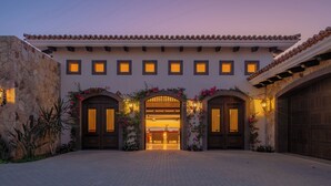 A building with a stone facade, multiple arched entrances, and a tiled roof. - Modern Diamante Golf Villa w/ Heated Pool, Hot Tub, Golf Cart & Ocean Views (Cabo San Lucas)