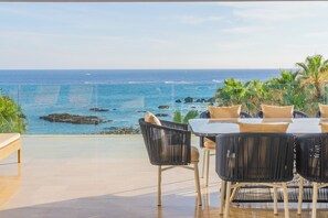 Eine Terrasse mit Meerblick, ausgestattet mit einem Tisch, Stühlen und einer Bank.