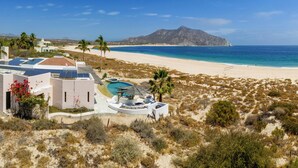 Un complexe hôtelier de bord de mer doté d’une piscine, de palmiers et d’une montagne en arrière-plan.