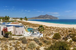 Ein Strandresort mit Pool, Palmen und Bergen im Hintergrund.