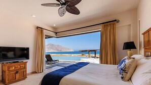 Une chambre avec un lit, une télévision et une vue sur la mer.
