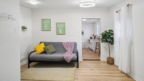 A modern living room with a grey sofa, a small rug, and a potted plant. - Stroll to the Dome: Sleek 1BR Near Downtown (San Antonio)