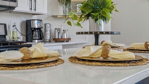 A kitchen counter with a white marble surface, a coffee maker, a microwave, and a potted plant. - Cozy Historic Gem: 5 Mins to Downtown SA (San Antonio)
