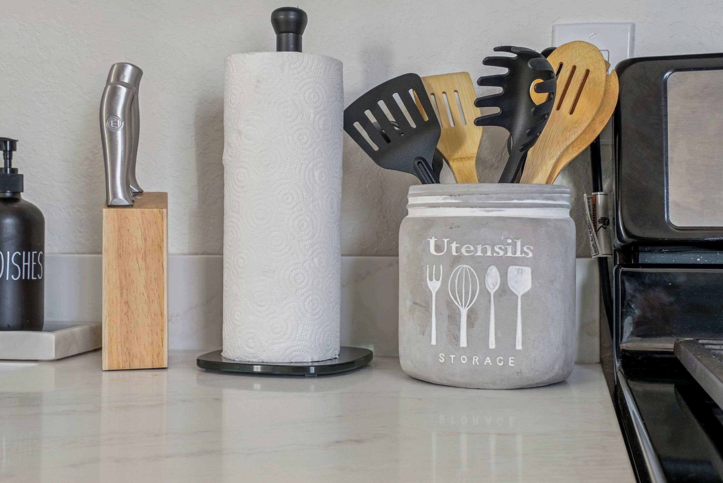 Een keukentrap met een keukenrolhouder, een messenblok, een kruidenpot en een pot voor keukengerei.