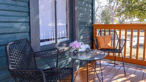 A wooden deck with two wicker chairs and a glass table, a toy car, and a pink flower on the table. - Cozy Historic Gem: 5 Mins to Downtown SA (San Antonio)