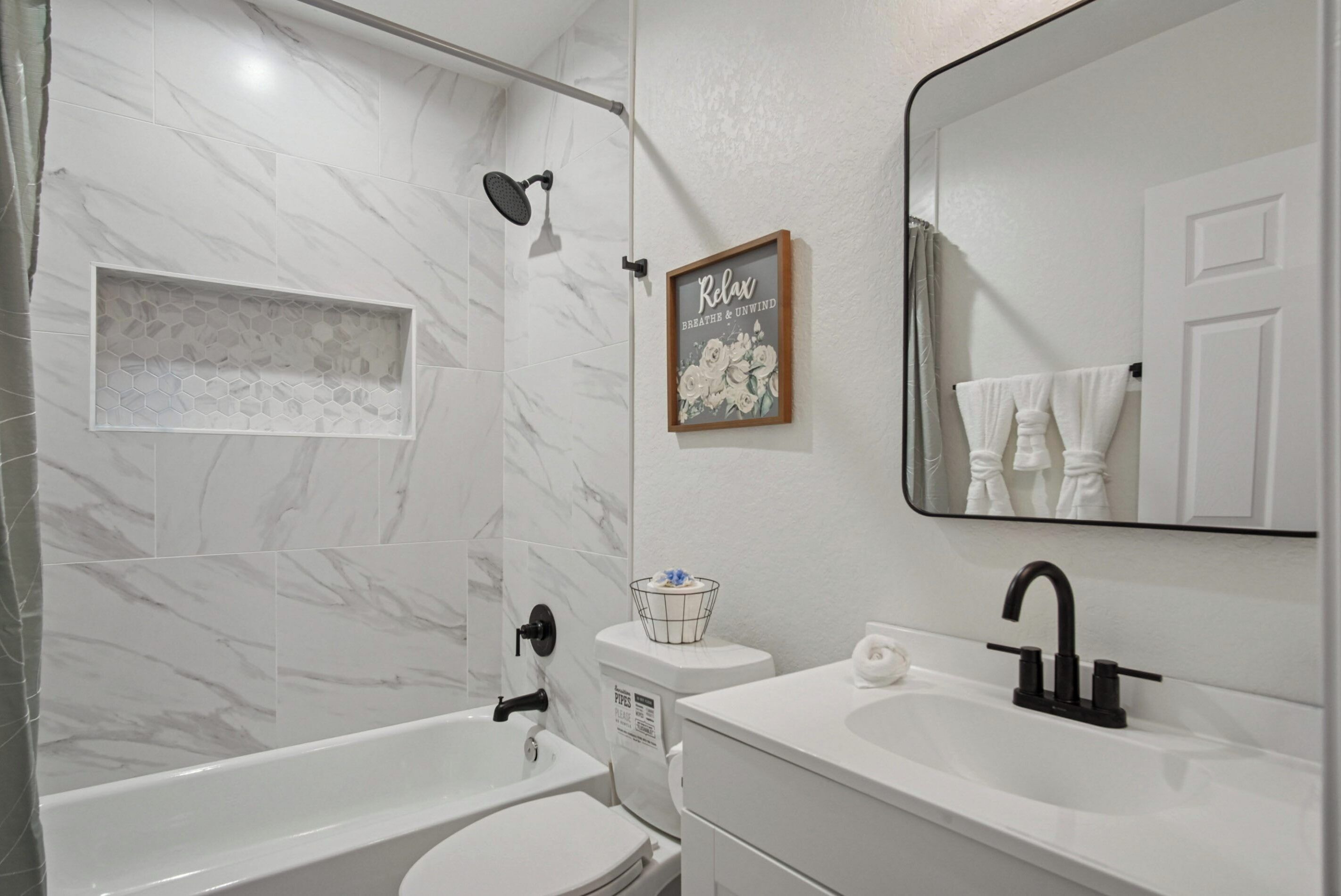 A bathroom with a shower, toilet, sink, and a mirror.