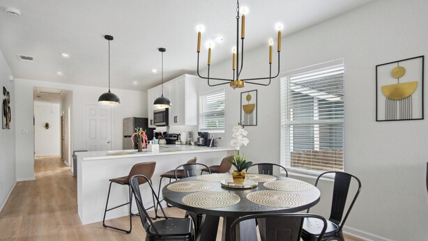 A modern kitchen with white cabinets, a central island, and a dining area with a round table and chairs. - Minutes to Downtown: Spacious 4br/3ba Historic Gem (San Antonio)
