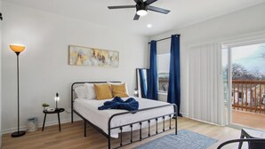 A bedroom with a bed, a floor lamp, a painting, a ceiling fan, and a view of the outdoors. - Minutes to Downtown: Spacious 4br/3ba Historic Gem (San Antonio)