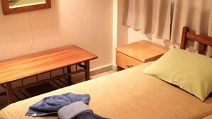 A hotel room with two beds, a wooden desk, a nightstand, and a mirror on the wall. - G Papanicola Tourist Apartments (Ayia Napa)