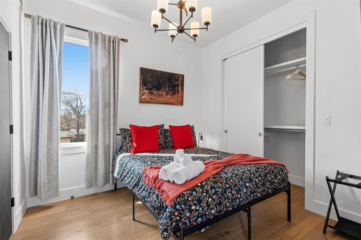 Quarto com cama, guarda-roupa, pintura e lustre.