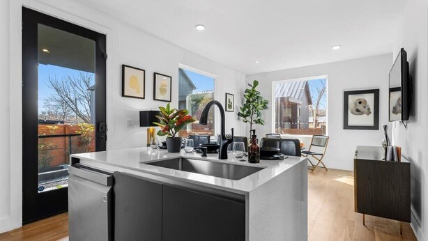 A modern kitchen with a central island, built-in appliances, and a dining area with a view. - Gladeview Dr (Austin)