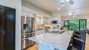 Una cocina moderna con electrodomésticos de acero inoxidable, encimera de mármol y un comedor con sillas de cuero negro.
