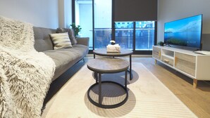 Ein modernes Wohnzimmer mit einer Couch, einem Couchtisch und einem Fernseher auf einem Lowboard.