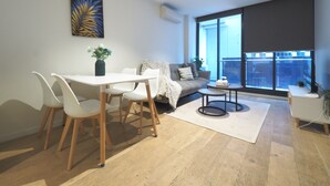 Ein modernes Wohnzimmer mit Essbereich, einer Couch, einem Couchtisch und einem großen Fenster mit Blick.