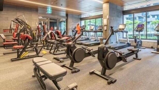 Ein Fitnessstudio mit Laufbändern, Kraftgeräten und Bänken.