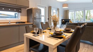 Una cocina moderna con comedor, incluyendo una mesa para dos personas con fuentes, vasos y un jarrón de flores.