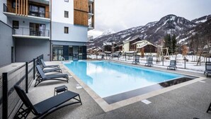 Een modern hotel met een zwembad, terras en uitzicht op de bergen.