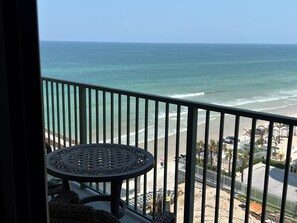 Een balkon met uitzicht op zee, een ronde tafel en een stoel.