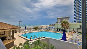 A pool area with lounge chairs and a view of the beach and ocean. - Feel the Sea Breeze, Stylish 2 BR Condo on the Beach W/ Pool (Daytona Beach)