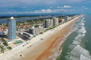 A coastal cityscape with a long sandy beach, high-rise buildings, and a clear view of the ocean. - Feel the Sea Breeze, Stylish 2 BR Condo on the Beach W/ Pool (Daytona Beach)