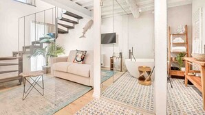 Una sala de estar moderna con una escalera, un sofá, una mesa de centro y un espejo grande.