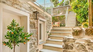 Una escalera de piedra que lleva a un balcón con mobiliario exterior.