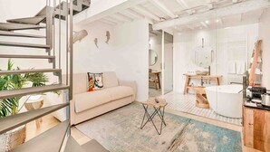 Un interior moderno con una escalera, un sofá, un comedor y un baño.