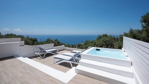 Une terrasse sur le toit avec une piscine, des chaises longues et une vue sur la mer.