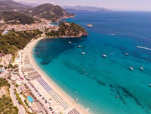 An aerial view of a coastal town with a beach, boats, and a small island.